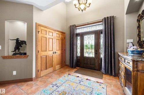 Entryway featuring a wood-paneled front door with decorative glass inserts and sidelights, a transom window, and a chandelier light fixture - 28125 Highway 587, Rural Red Deer County, AB 