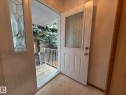 Entryway featuring a white door with decorative glass paneling, a matching sidelight, and wood-finish trim - 102 4610 50 Avenue, Stony Plain, AB 
