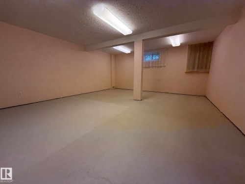 Spacious room with concrete flooring and light-toned walls - 102 4610 50 Avenue, Stony Plain, AB 