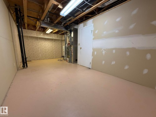 Unfinished basement space featuring exposed ceiling joists, utility systems, and a combination of finished and unfinished walls - 102 4610 50 Avenue, Stony Plain, AB 