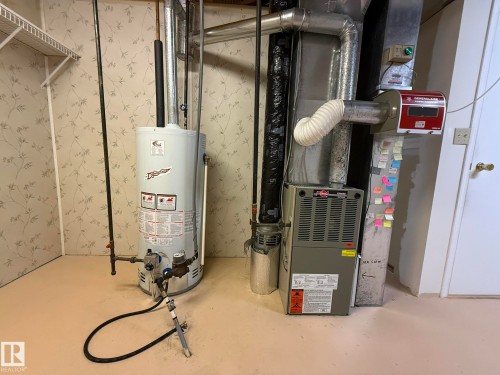 Dedicated utility area featuring a water heater, furnace, and associated ductwork - 102 4610 50 Avenue, Stony Plain, AB 