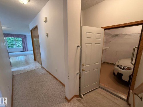 Entryway featuring patterned carpeting, wood-finish flooring, and a flush-mount ceiling light - 102 4610 50 Avenue, Stony Plain, AB 