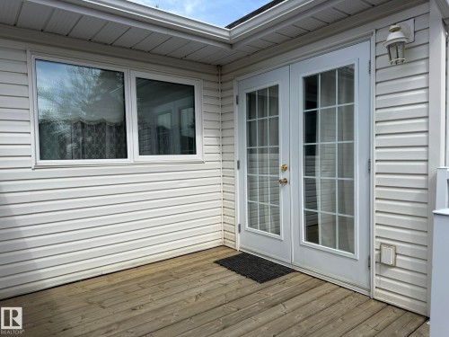 Wood-finish deck featuring white vinyl siding and white-framed windows - 102 4610 50 Avenue, Stony Plain, AB 