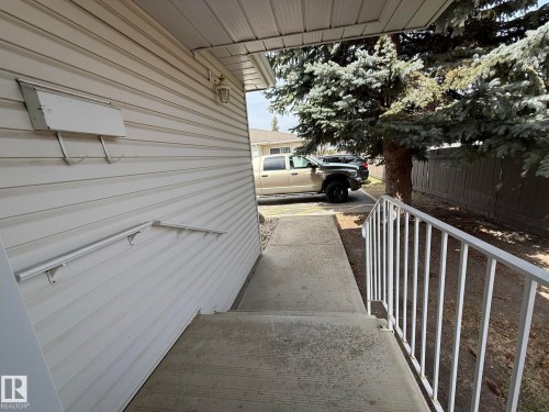 Exterior entrance with concrete steps and an aluminum handrail - 102 4610 50 Avenue, Stony Plain, AB 
