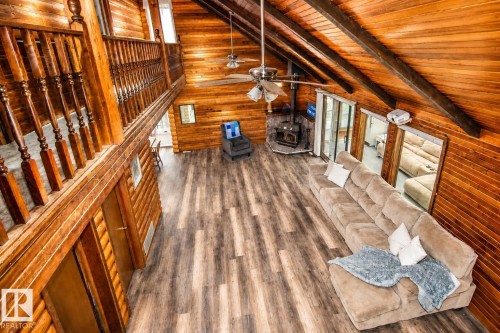 Spacious living area featuring extensive natural wood paneling throughout, wood-finish flooring, and a vaulted ceiling with exposed beams - 61 Stang Cres, Rural Two Hills County, AB 