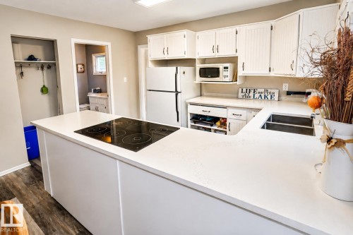 Kitchen featuring white cabinetry with dark hardware, a built-in cooktop, and light-toned countertops - 61 Stang Cres, Rural Two Hills County, AB 