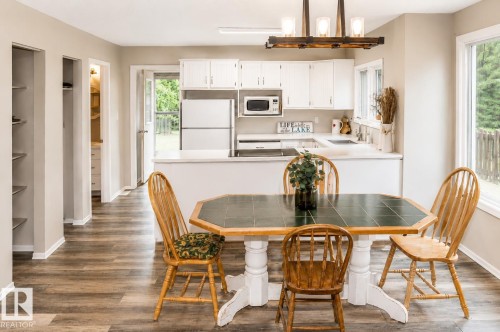 Open-concept kitchen and dining area featuring wood-finish flooring, white cabinetry, and white countertops - 61 Stang Cres, Rural Two Hills County, AB 