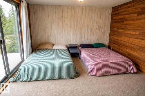 Carpeted room featuring a full wall of sliding glass doors, vertical paneling, and wood-finish accent wall - 61 Stang Cres, Rural Two Hills County, AB 
