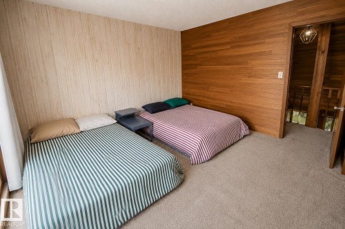Carpeted room featuring a light wood-finish accent wall and a darker wood-finish wall - 61 Stang Cres, Rural Two Hills County, AB 