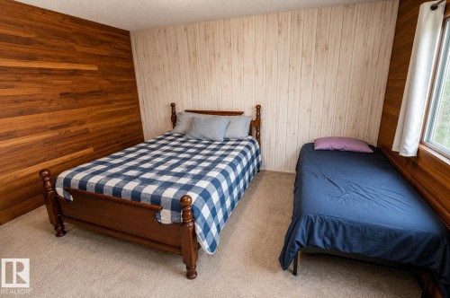 Carpeted room featuring a window, wood-paneled walls, and shiplap-style wall covering - 61 Stang Cres, Rural Two Hills County, AB 