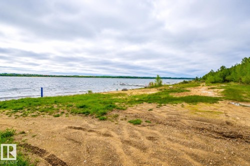Waterfront property featuring a natural shoreline with interspersed green grass and sandy areas - 61 Stang Cres, Rural Two Hills County, AB 