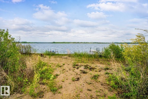 Waterfront property featuring a small dock, sandy shoreline, and natural vegetation - 61 Stang Cres, Rural Two Hills County, AB 