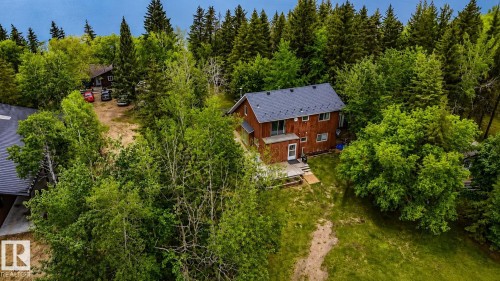 Two-story residence featuring a wood-panel exterior and a dark shingle roof, set among mature trees - 61 Stang Cres, Rural Two Hills County, AB 