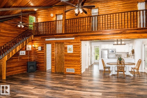 Vaulted wood-paneled ceiling with exposed beams, wood-finish flooring, and a stone-look electric fireplace - 61 Stang Cres, Rural Two Hills County, AB 