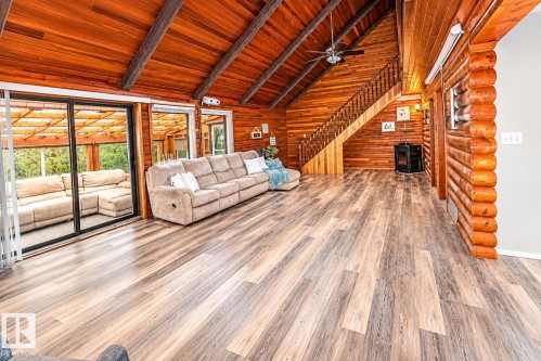 Open-concept living space featuring wood-finish flooring, vaulted wood plank ceilings with exposed beams, and a wood staircase - 61 Stang Cres, Rural Two Hills County, AB 