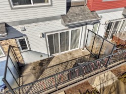 Outdoor patio area featuring a concrete surface, black metal railing with glass panels, and sliding glass door access - 