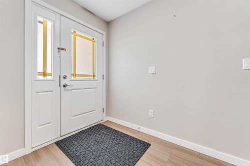 Entryway featuring a white paneled front door with a transom window, a sidelight, and light-toned tile flooring - 1624 33A Street, Edmonton, AB 