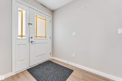 Entryway featuring a white paneled front door with a transom window, a sidelight, and light-toned tile flooring - 