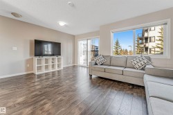 Spacious living area featuring wood-finish flooring, a large window, and a sliding glass door - 
