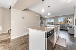 Kitchen island featuring a stainless steel dishwasher, an undermount sink with a high-arc faucet, and pendant lighting - 