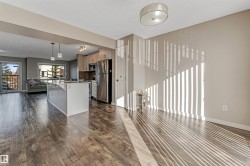Open-concept living area with wood-finish flooring, a kitchen island, stainless steel appliances, and a private balcony - 