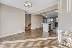 Open-concept living area featuring wood-finish flooring, a contemporary ceiling light fixture, and neutral wall tones - 