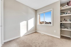 Neutral-toned room featuring a window with white trim, built-in shelving, light brown carpeting, and white baseboards - 