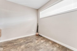 Neutral-toned walls featuring a horizontal window with blinds, wood-finish flooring, and white baseboards - 