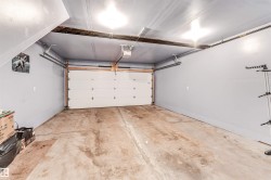 Spacious garage featuring a concrete floor, light gray painted walls, and an automatic overhead door - 
