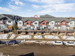 Contemporary townhome exterior featuring light siding, red accent panels, and gray shingle roofing - 
