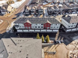 Townhome complex featuring white facades with red and grey accents, individual garage access, asphalt shingle roofing, and integrated balconies - 