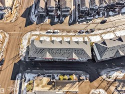 Aerial perspective showcasing a multi-unit residential building with light gray shingled roofs and dark gray siding - 
