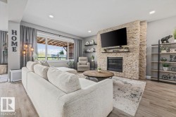Living area featuring a floor-to-ceiling stacked stone fireplace, a large picture window, recessed lighting, and neutral palette - 