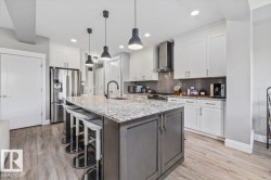 Spacious kitchen featuring a large island with a granite countertop, white upper and lower cabinetry, stainless steel appliances, and natural gas range - 