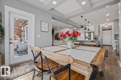 Dining area featuring a coffered ceiling with recessed lighting, LVP flooring, and a patio door leading to an outdoor living space - 