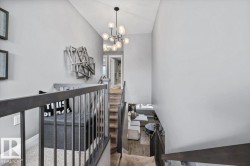 Multi-level interior featuring a contemporary chandelier, hardwood-style flooring, and carpeted stairs with dark wood railings - 