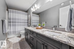 Bathroom featuring a double vanity with granite countertops, modern cabinetry and double sinks - 