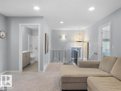 Carpeted loft area featuring recessed lighting, a modern chandelier, and a black wrought iron railing - 207 41 Avenue, Edmonton, AB 