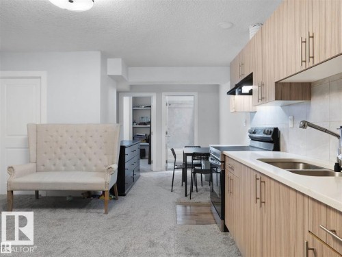 Functional kitchen featuring wood-finish cabinetry, light-toned countertops, and a stainless steel sink with a pull-down faucet - 207 41 Avenue, Edmonton, AB 