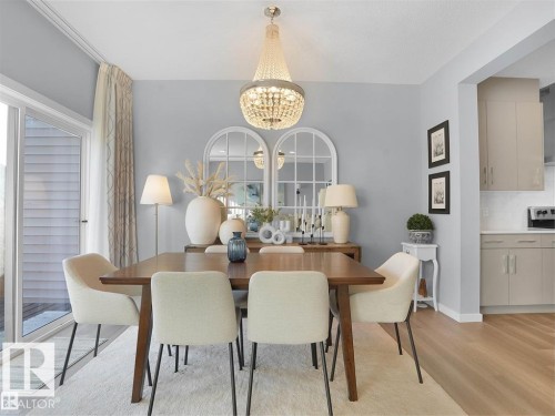 Dining area featuring a crystal chandelier, light blue wall paint, and wood-finish flooring - 207 41 Avenue, Edmonton, AB 