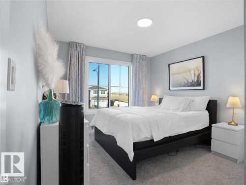 Bedroom featuring carpet flooring, a large window with drapes, and a built-in ceiling light - 207 41 Avenue, Edmonton, AB 