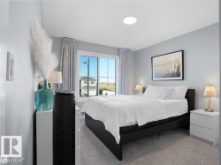 Bedroom featuring carpet flooring, a large window with drapes, and a built-in ceiling light - 