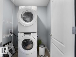 Dedicated laundry closet featuring a stacked washer and dryer, white wire shelving, and light gray wall paint - 