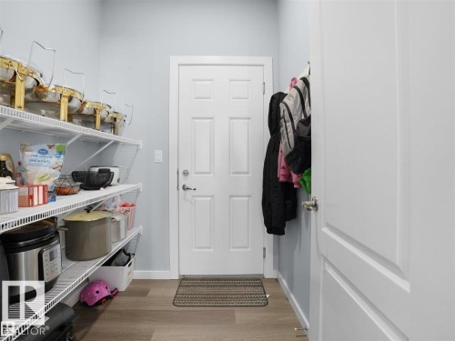 Walk-in pantry featuring wire shelving, wood-finish flooring, and a six-panel interior door - 207 41 Avenue, Edmonton, AB 