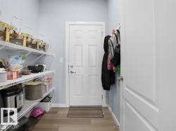 Walk-in pantry featuring wire shelving, wood-finish flooring, and a six-panel interior door - 