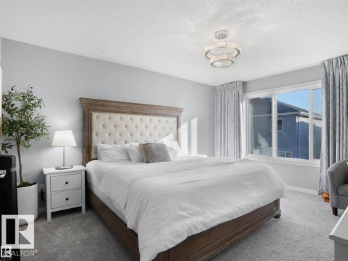 Spacious bedroom featuring light gray walls, plush carpeting, a large window, and a contemporary ceiling fixture - 207 41 Avenue, Edmonton, AB 
