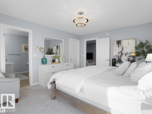 Plush carpet flooring, a contemporary chandelier, and light blue wall tones define this inviting bedroom - 207 41 Avenue, Edmonton, AB 