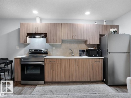 Kitchen featuring wood-finish cabinetry, light-toned countertops, and a tile backsplash - 207 41 Avenue, Edmonton, AB 