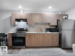 Kitchen featuring wood-finish cabinetry, light-toned countertops, and a tile backsplash - 