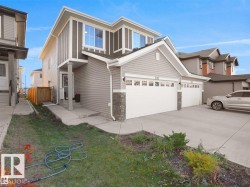 Modern two-story residence with a gray siding exterior, white trim accents, and a stone veneer foundation - 